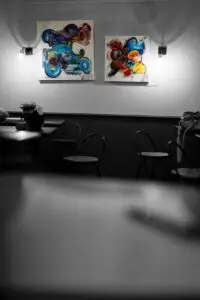 Deux tableaux abstraits et colorés de Sabine Noël accrochés au mur d’un espace d’exposition, photographie en noir et blanc partiellement colorisée